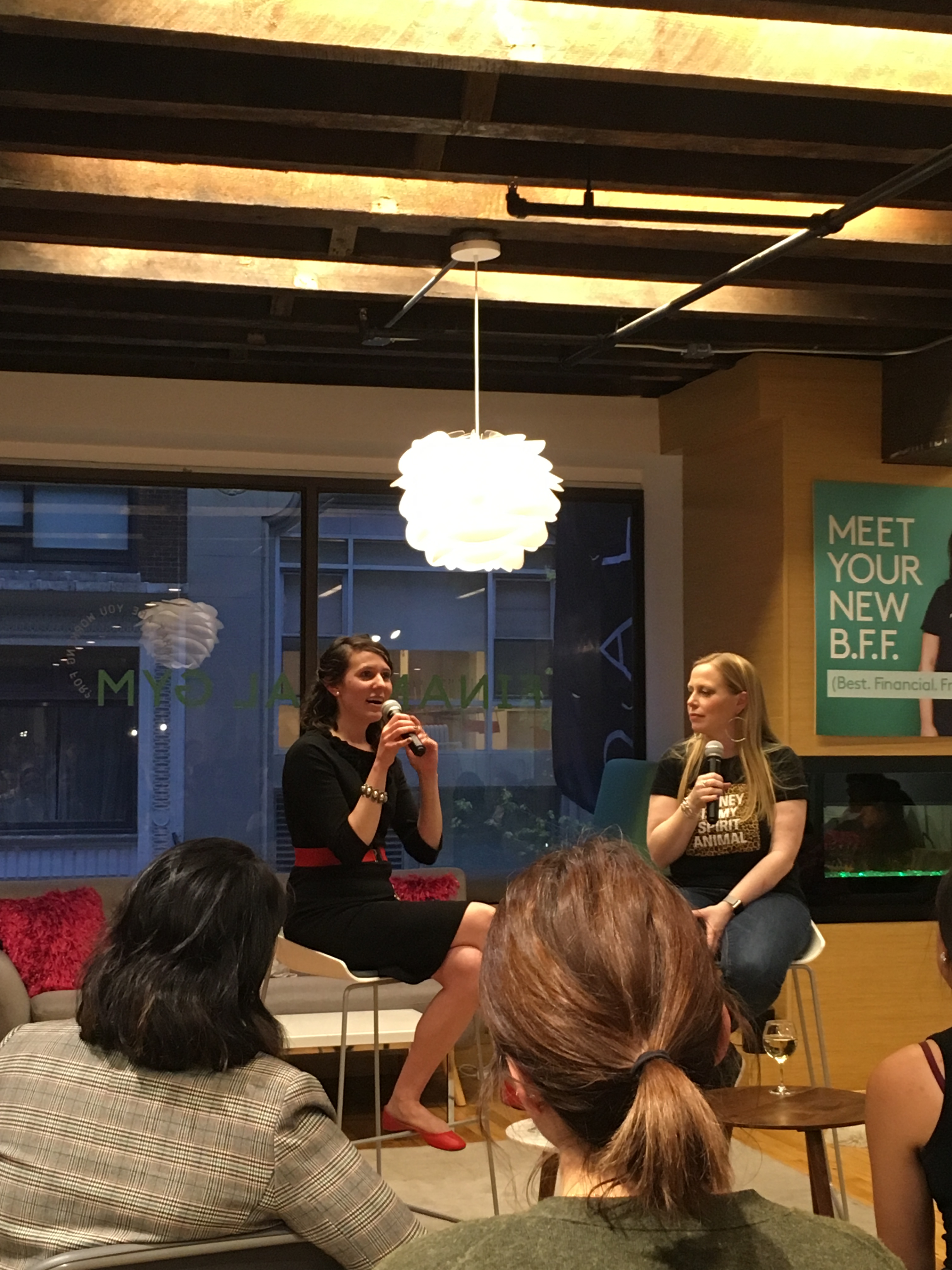 Two women are sitting on stools with microphones. On the left is blogger Mrs. Frugalwoods. On the right is the founder of the Financial Gym.